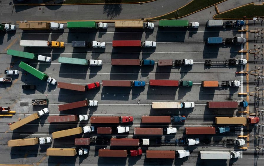 A line of trucks wait at a port.
