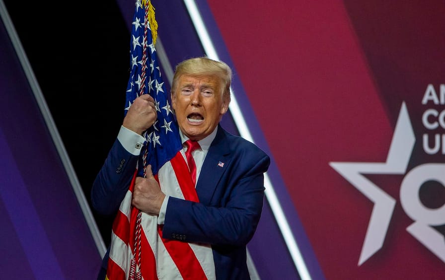 Donald Trump hugs the flag of the United States of America at the annual Conservative Political Action Conference in 2020.