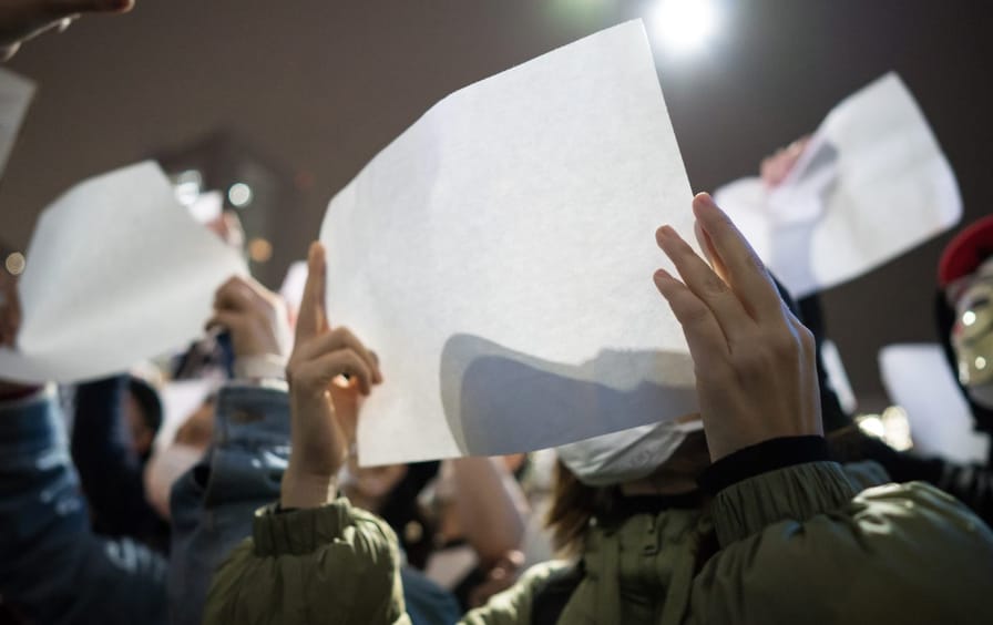 People in Tokyo hold up blank protest signs in solidarity with mainland Chinese protesters.