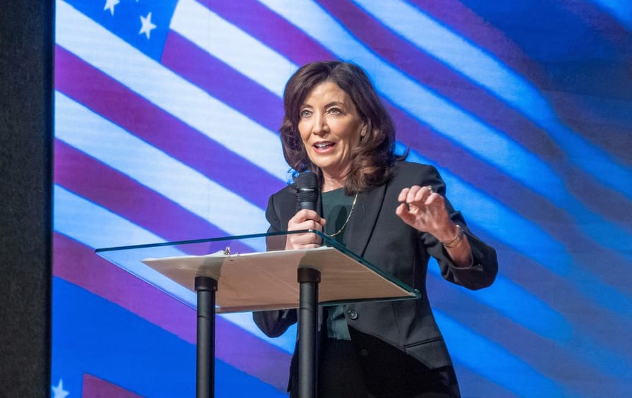 Kathy Hochul on stage in front of a projected American flag