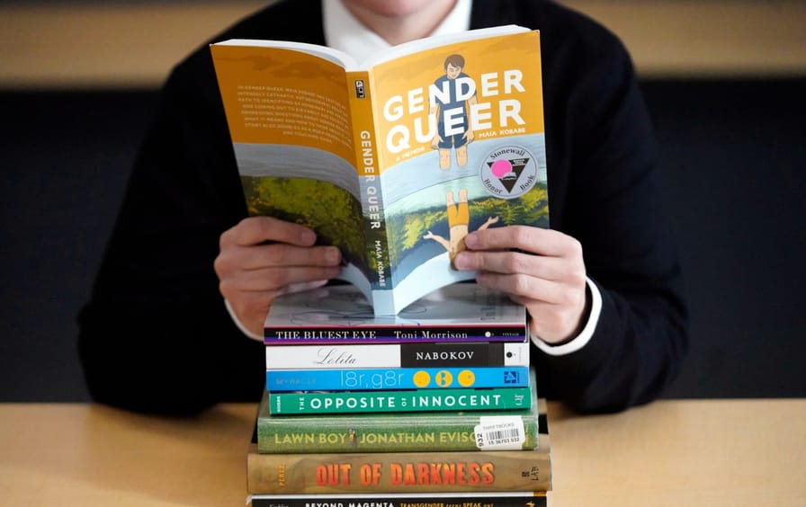 Person reads a stack of explicit or LGBTQ books