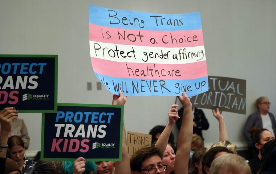 Young people holding signs in protest of Florida's anti-trans legislation.