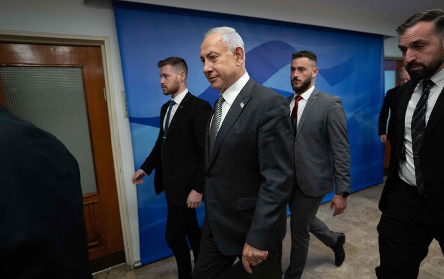 Benjamin Netanyahu walking down a hallway.