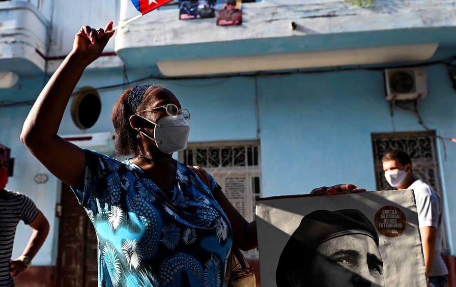 An elderly woman waves a Cuban flag holding a poster of Cuban late leader Fidel Castro in Havana, on July 26, 2021.