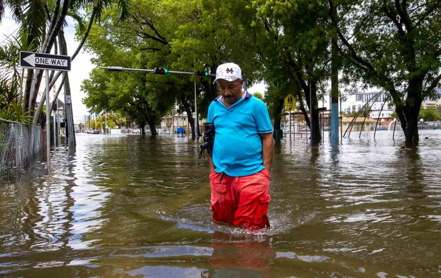 man crosses flooded street in Miami