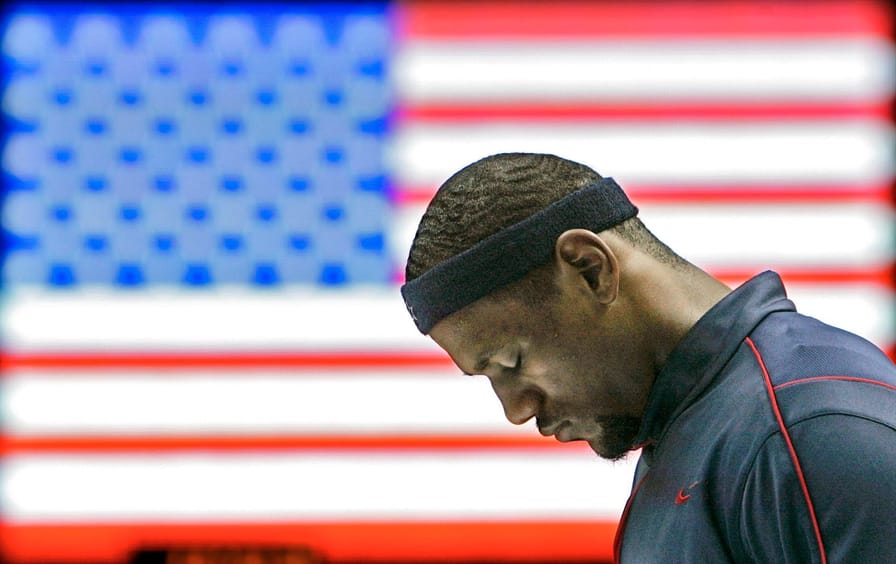 LeBron James stands in front of a monitor that shows the American flag.