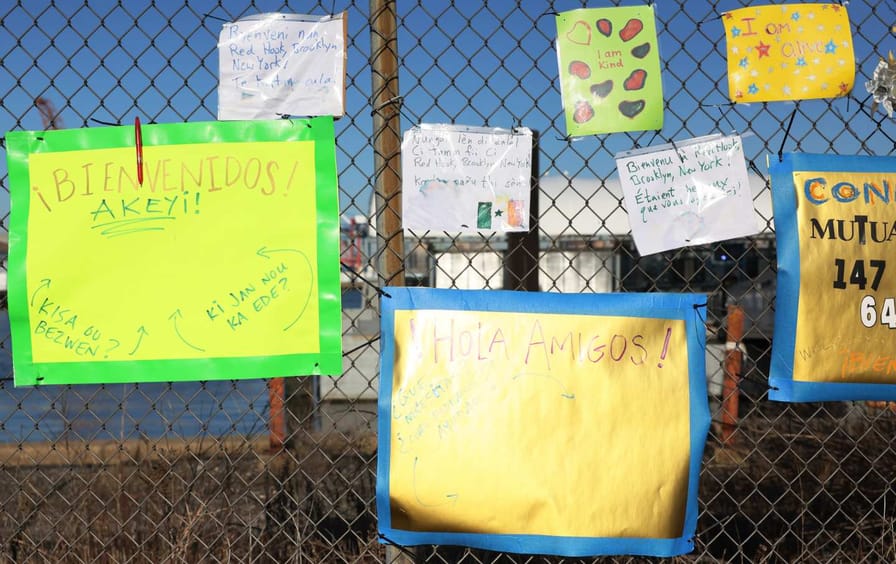 Signs welcoming migrants on a chain-link fence