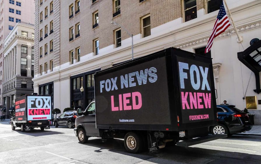 Aanplakborden van vrachtwagens rijden langs het Palace Hotel om de ontkenning van de verkiezing van Fox News af te keuren