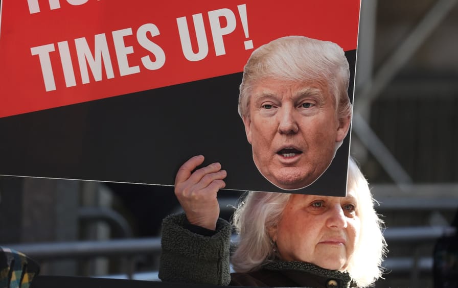 woman holds anti-Trump sign