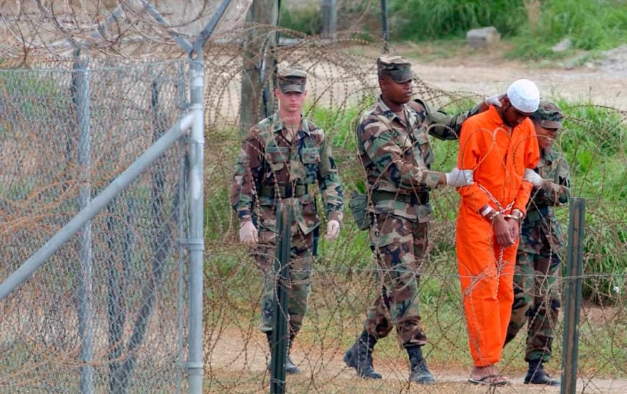 Een soldaat leidt een gevangene naar Guant'namo Bay