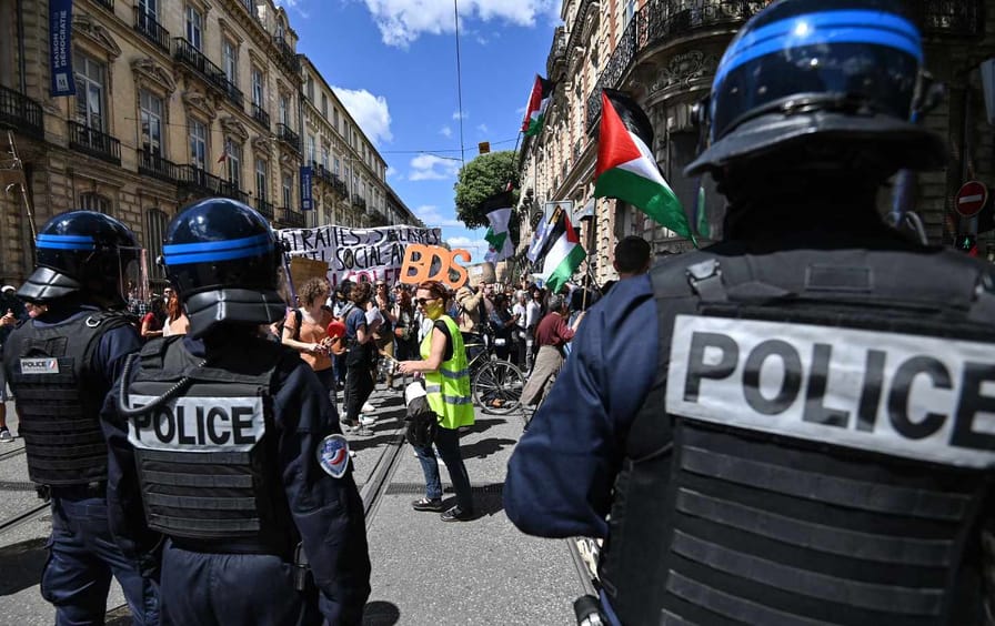 Riot police stand by as protesters brandish a placard for the Boycott, Divestment, and Sanctions movement during a May Day march in Montpellier, France, on May 1, 2023.