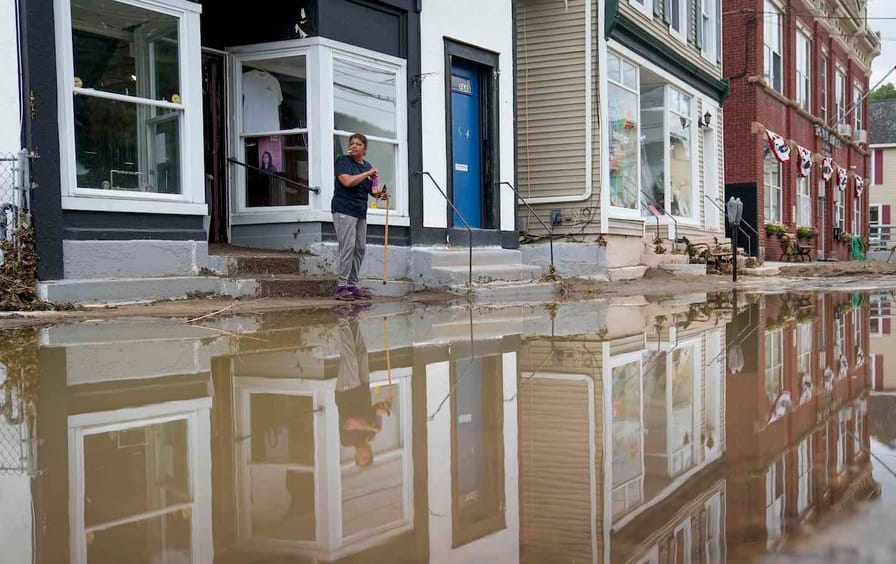 Kathy Eason, a worker at the Center for Highland Falls, stands outside the organization's storefront after being trapped inside by floodwaters the previous day, Monday, July 10, 2023, in Highland Falls, N.Y.