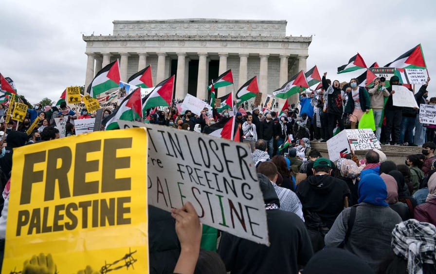 protesters gather outside lincoln memorial with signs reading 'free palestine,' palestinian flags