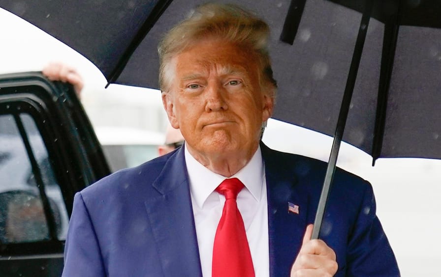 Trump holds an umbrella, walks to plane