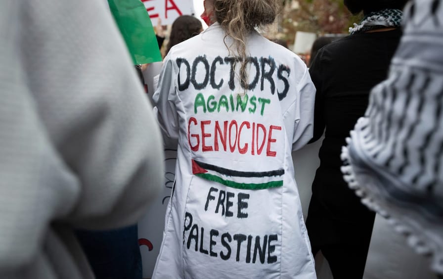 A doctor at a protest wearing a lab coat with 
