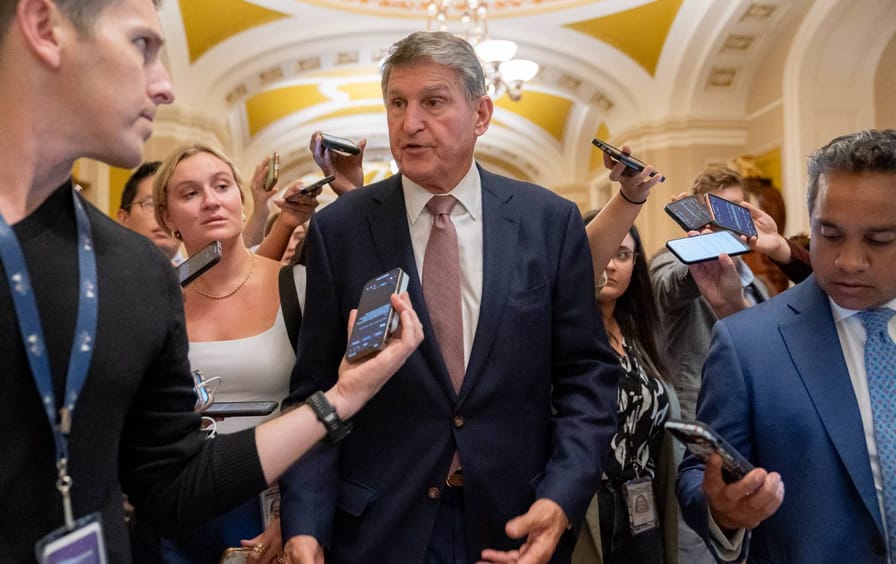 Joe Manchin surrounded by reporters in the Capitol building.