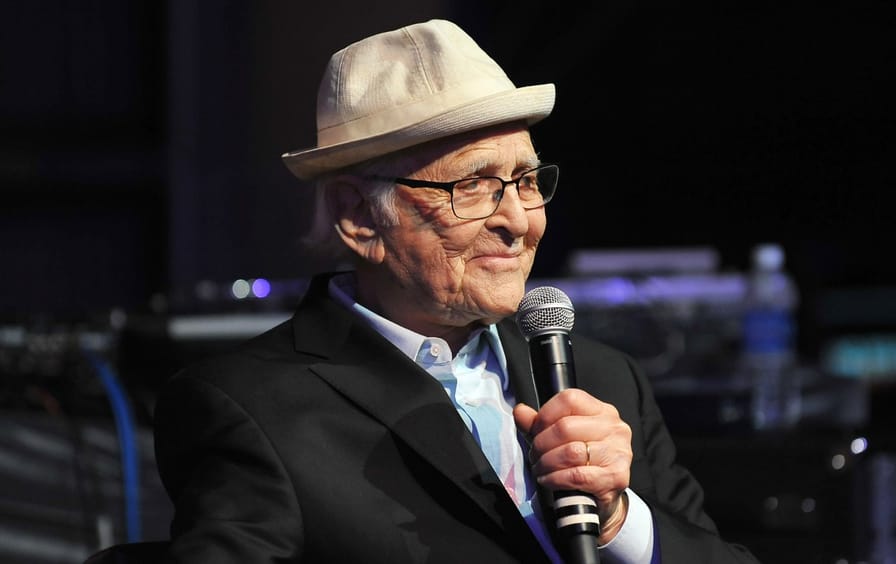 Norman Lear speaking on stage, holding a microphone.