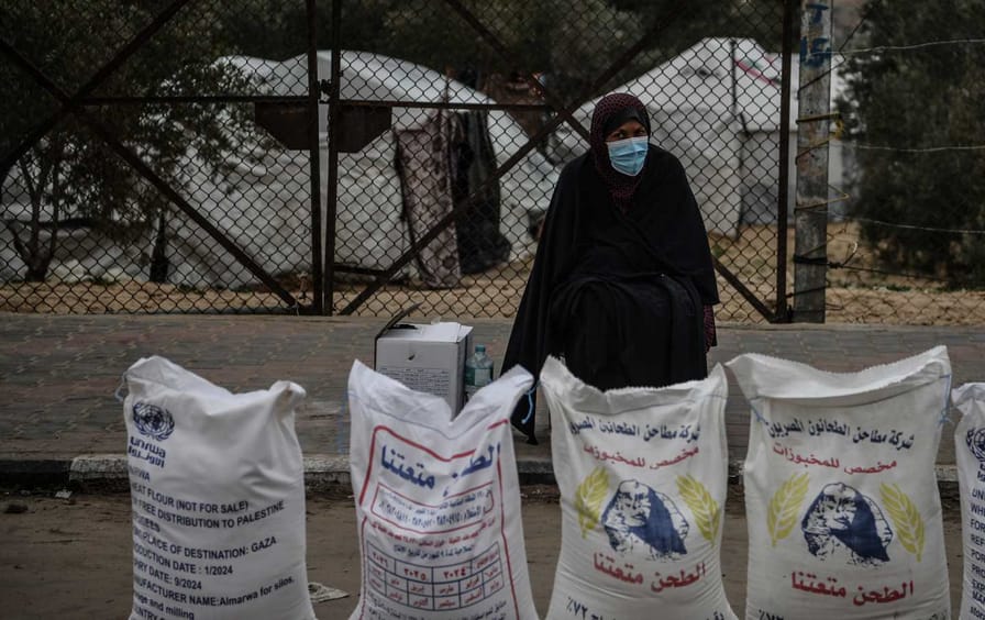A Palestinian woman stands by bags of flour distributed by the United Nations Relief and Works Agency at a refugee settlement in the Gazan city of Rafah.