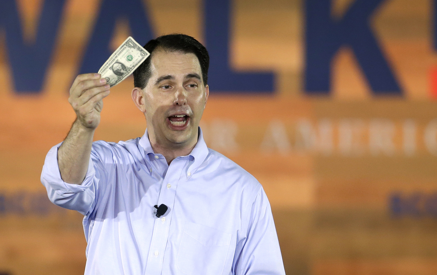 Wisconsin Governor Scott Walker holds a dollar bill as he announces his 2016 Republican presidential campaign.