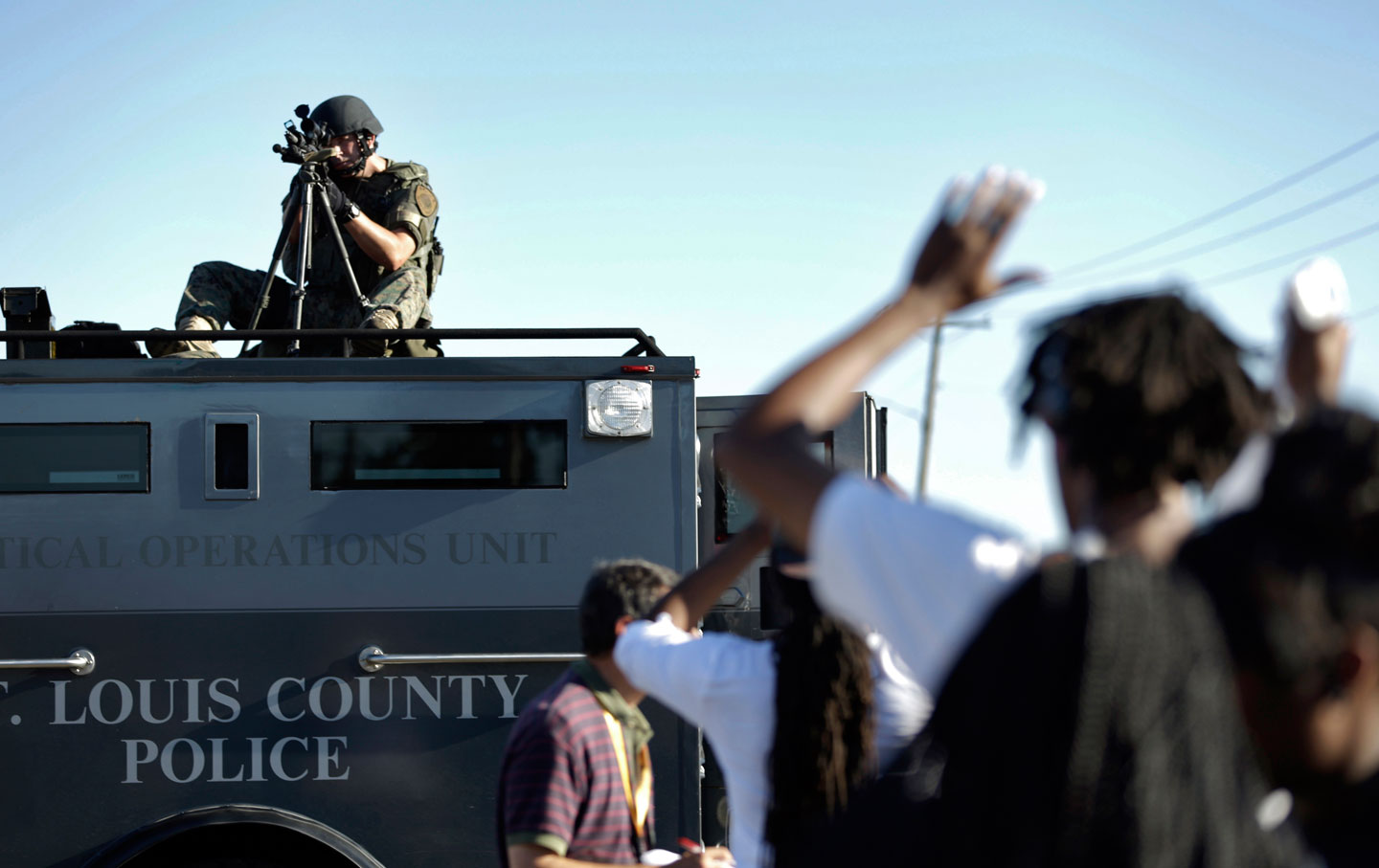 A member of the St. Louis County Police Department points his weapon in the direction of a group of protesters in Ferguson, MO.