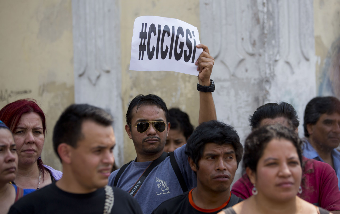 A man holds up a sign that reads in Spanish: 