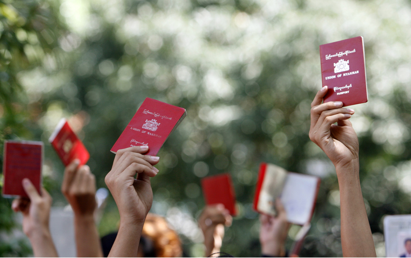Myanmar nationals hold up their passports outside the embassy of Myanmar in Singapore