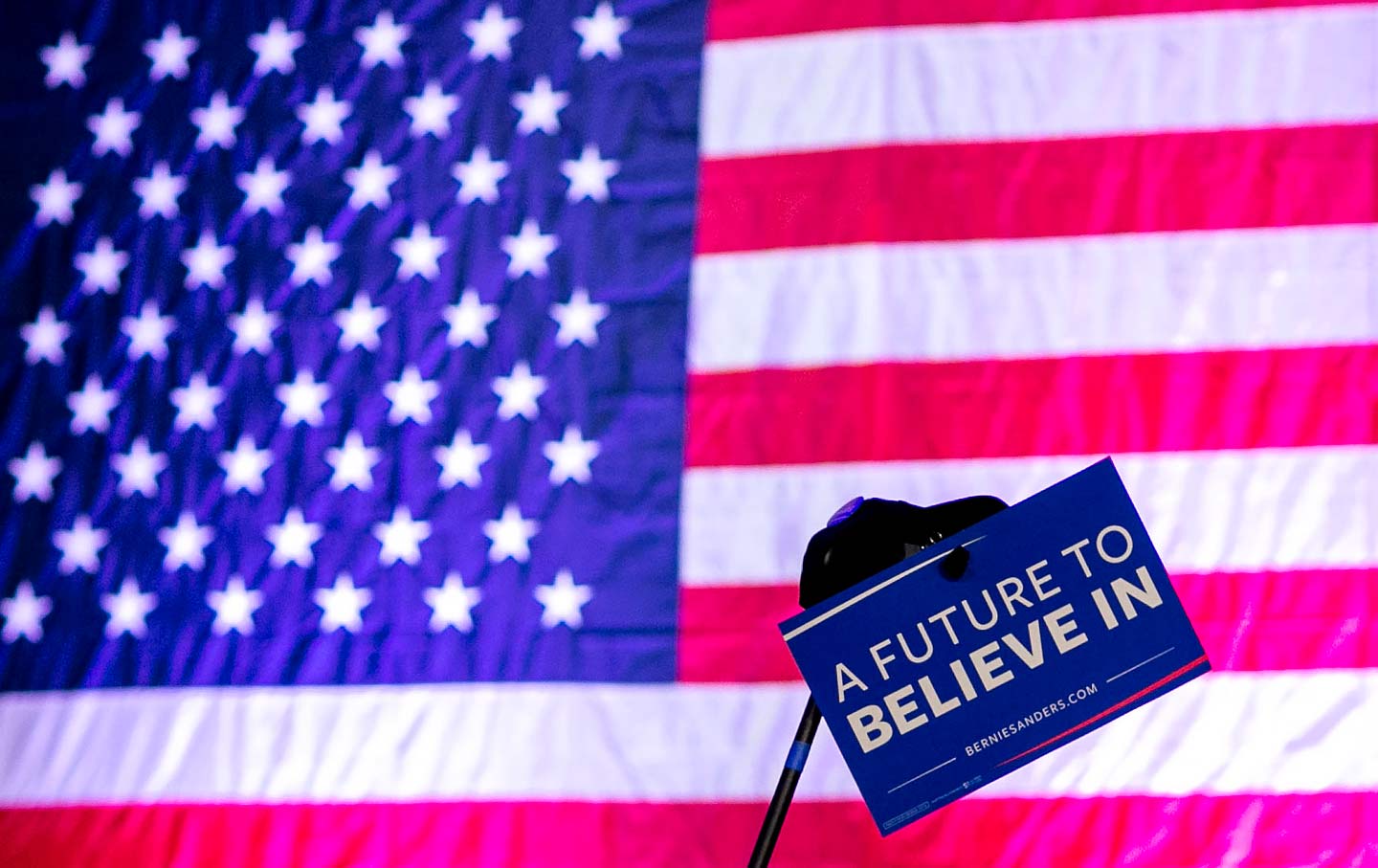 Bernie Sanders sign held in front of flag