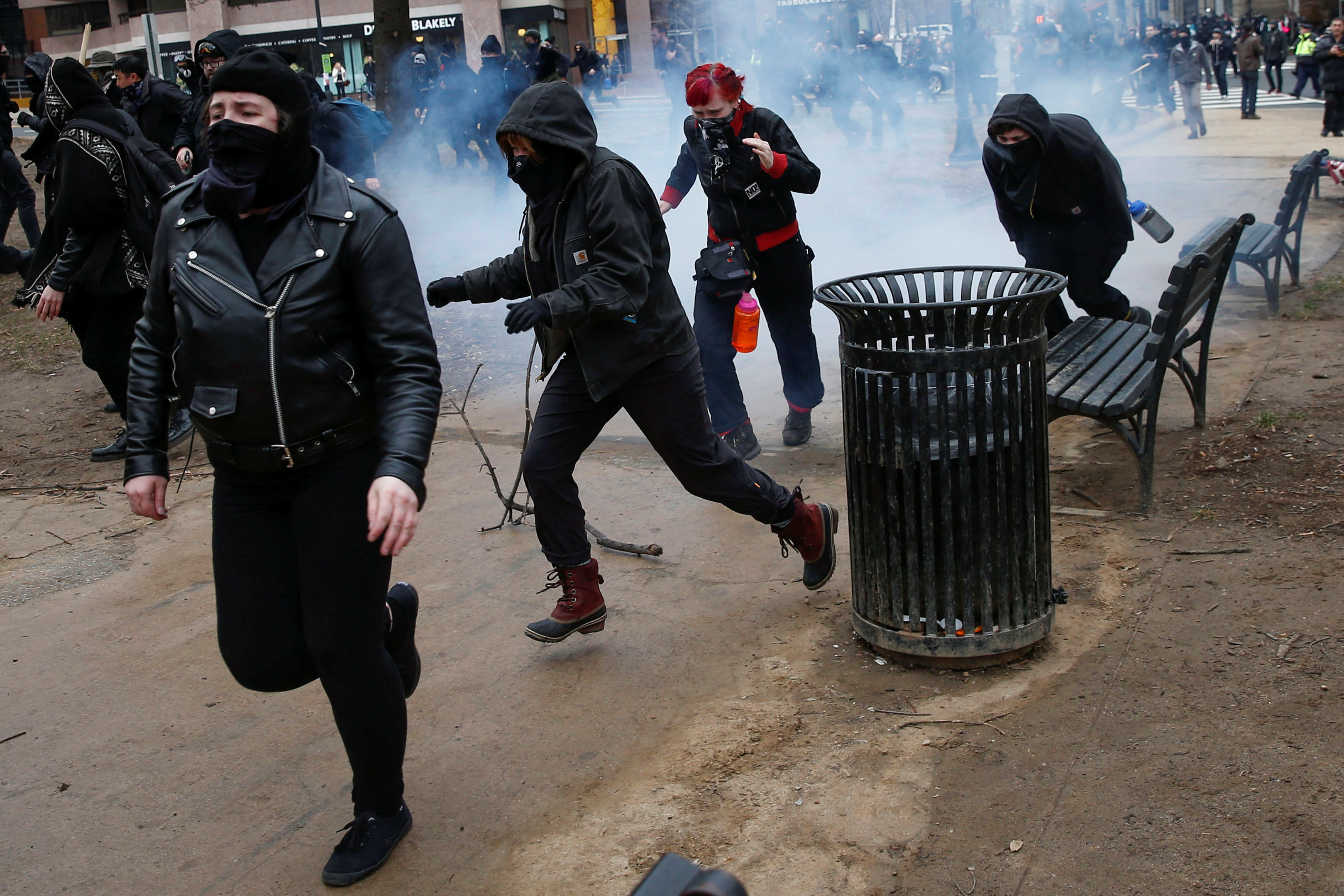 Activists run after being hit by a stun grenade while protesting against U.S. President-elect Donald Trump on the sidelines of the inauguration in Washington.