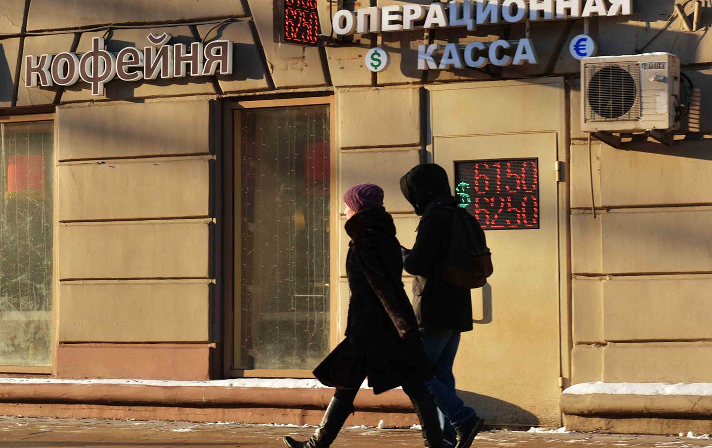 Two Russian civilians walking past a cash office in Moscow
