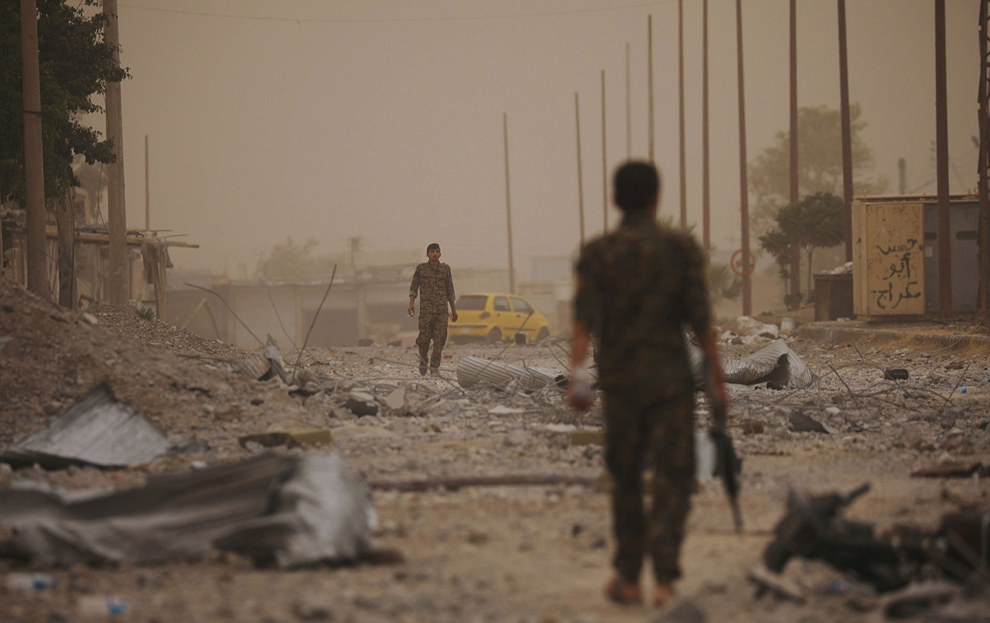 Syrian Democratic Forces (SDF) fighters walk on the rubble of a damaged street in Raqqa, Syria on June 14, 2017.