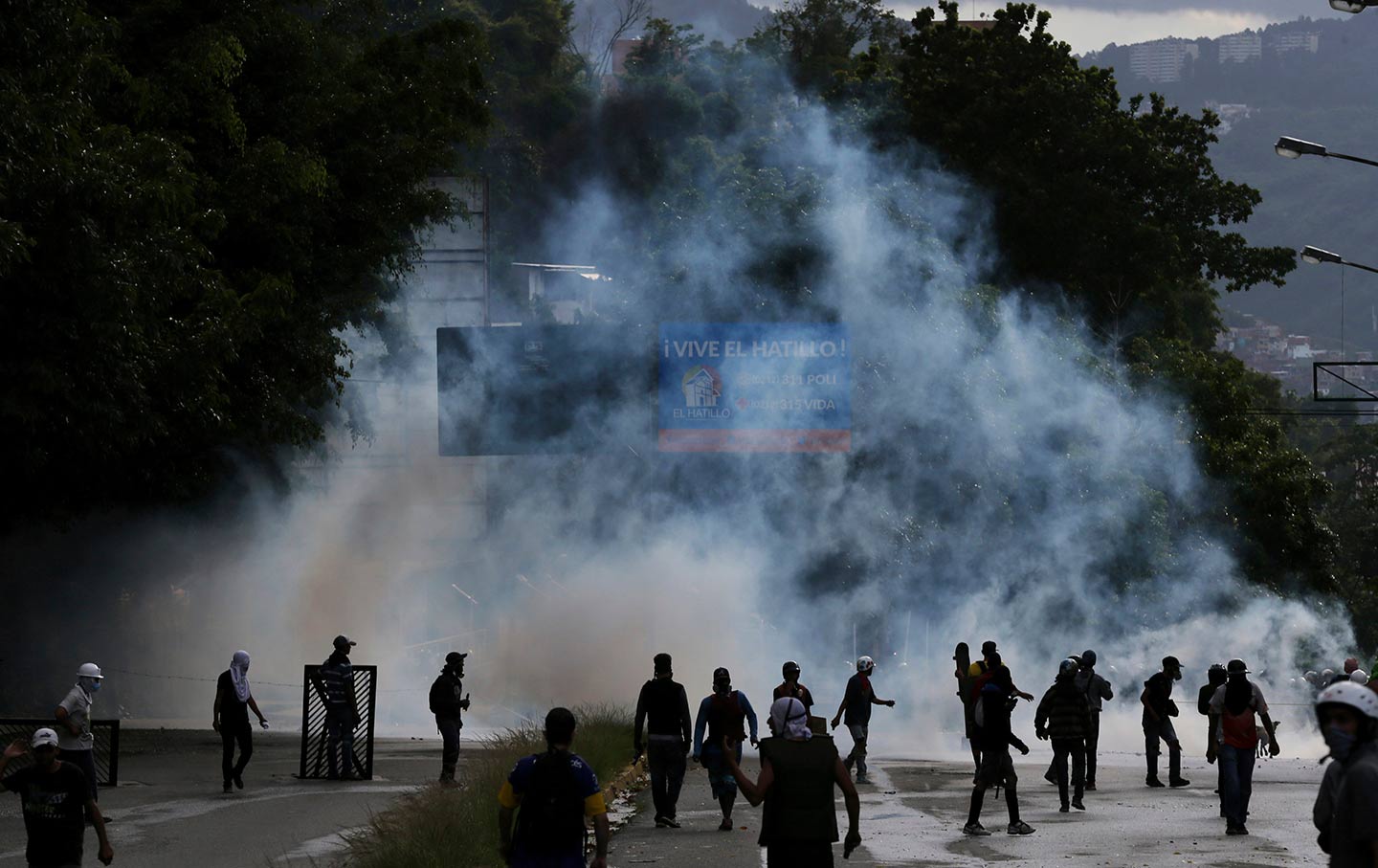 Demonstrators walk amid tear gas fired by Bolivarian National Guards on the outskirts of Caracas, Venezuela on July 20, 2017.