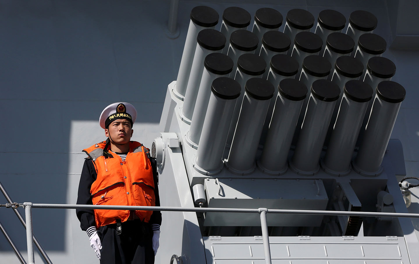 Chinese naval officer stands next to rocket launcher