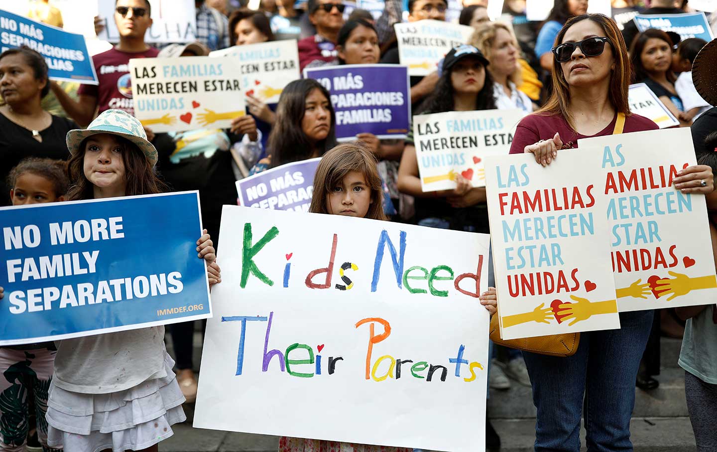 People hold signs to protest against President Donald Trump's executive order to detain children crossing the southern US border and separating families.