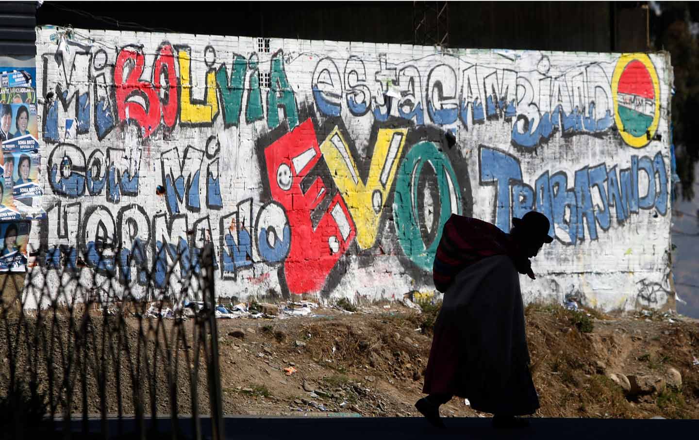Elderly woman walks past a mural celebrating Bolivian president Evo Morales