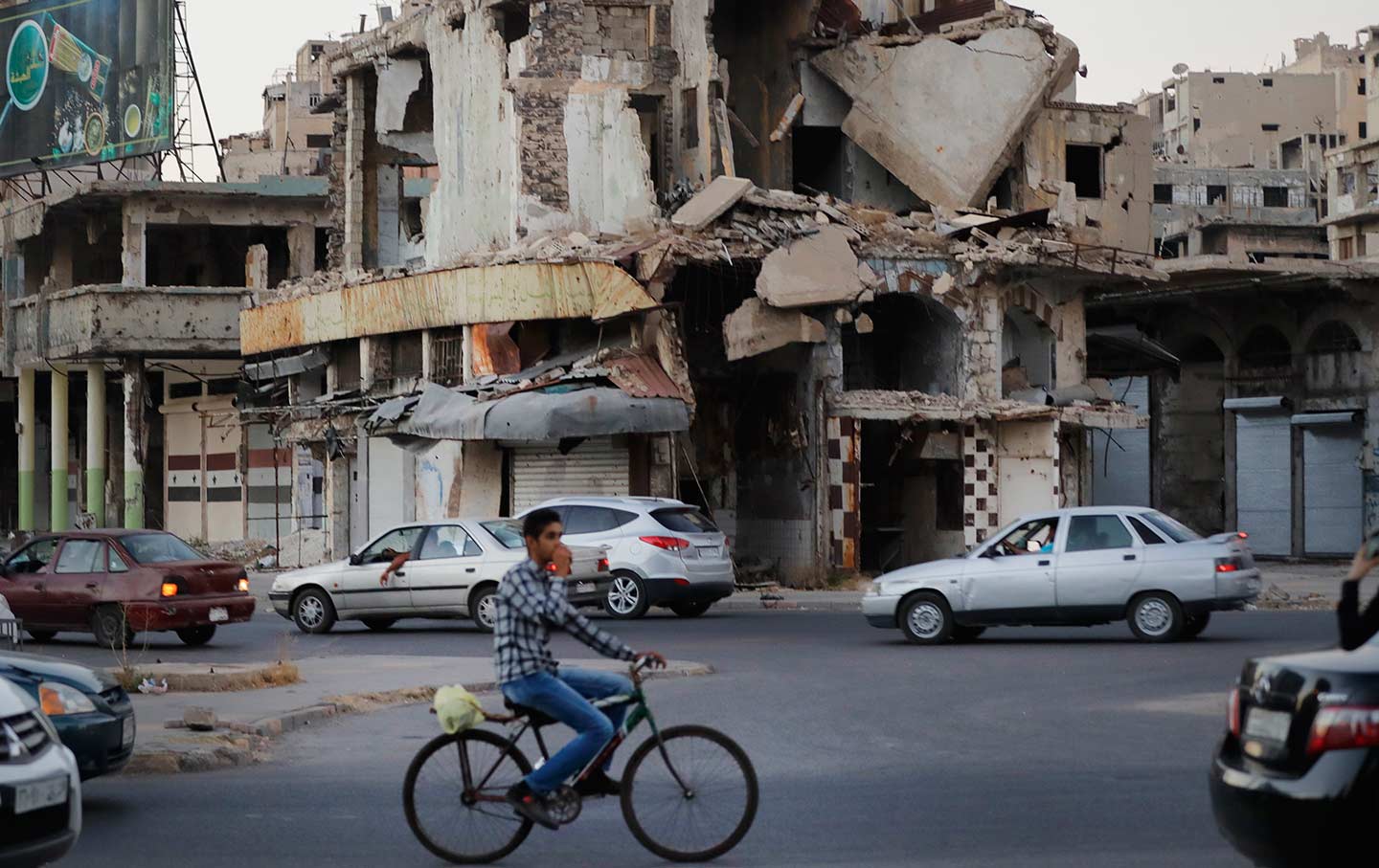 A man rides his bike past damaged buildings in the old town of Homs, Syria, on August 15, 2018.