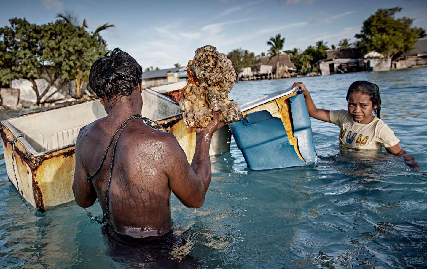 Man holds retrieves piece of rock from ocean