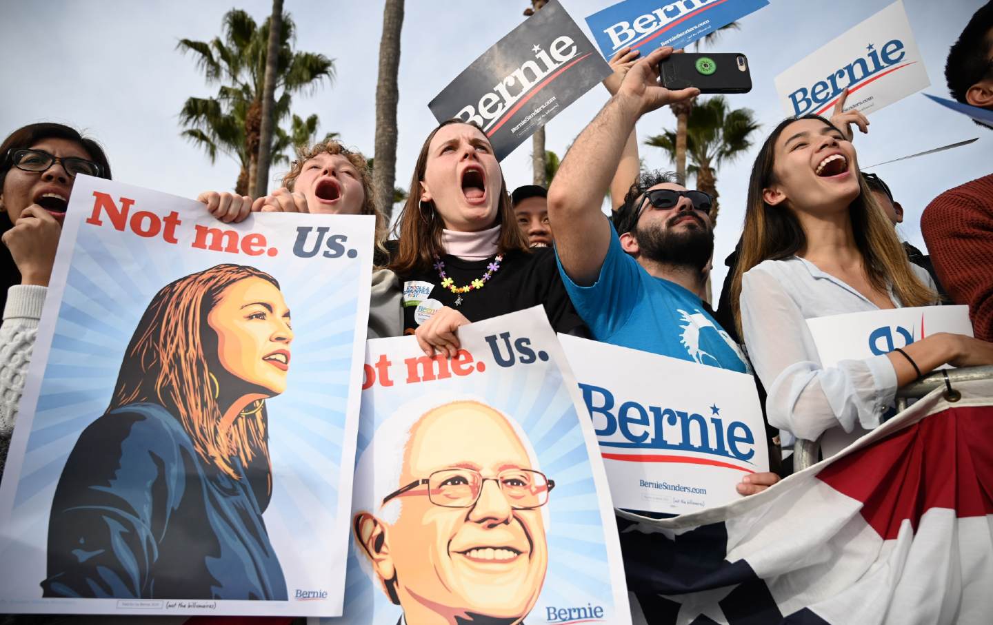 Bernie supporters at a rally, holding posters.