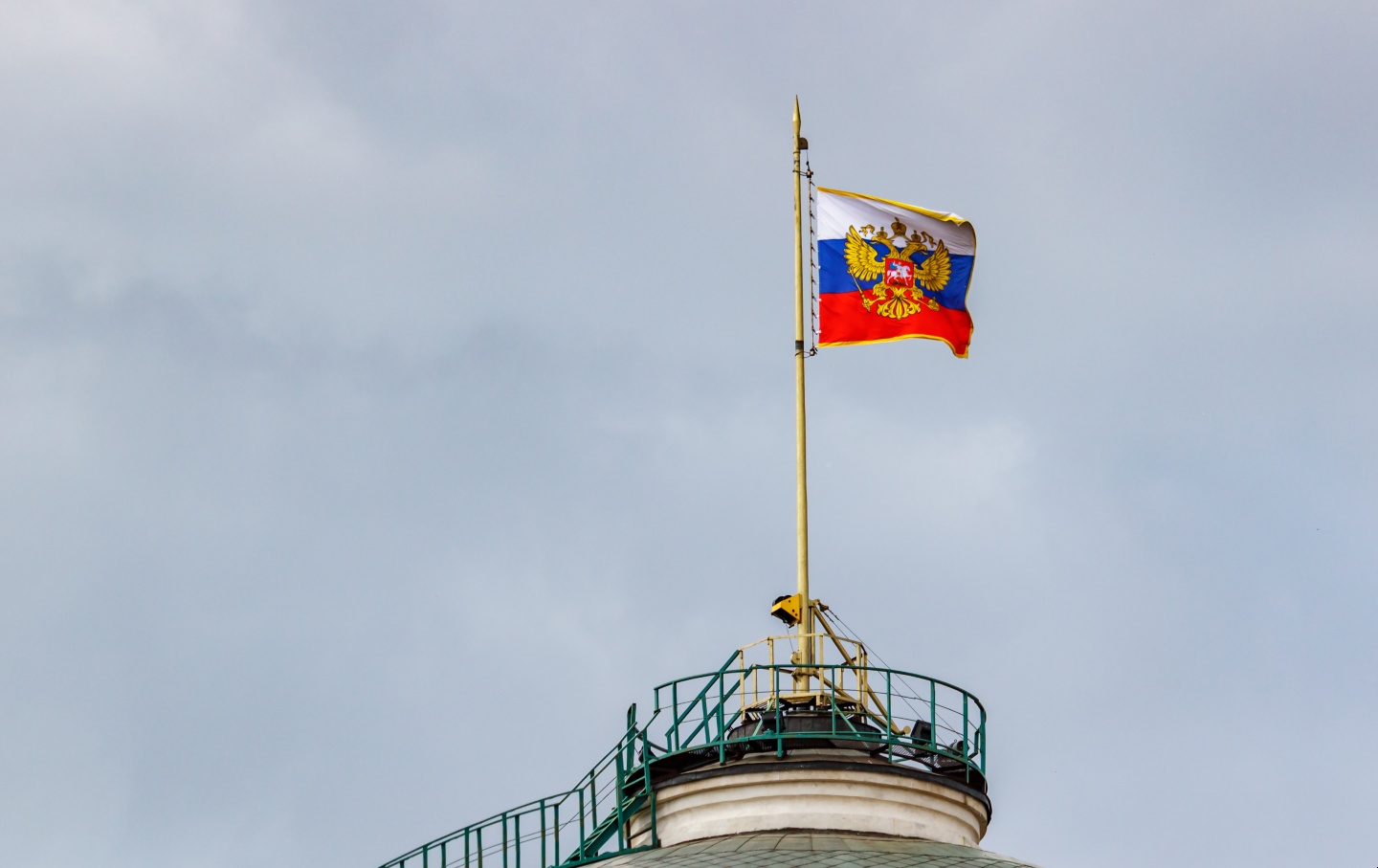 Flag of Russian Federation with gilded coat of arms waving on the dome of Senate Palace of Moscow Kremlin