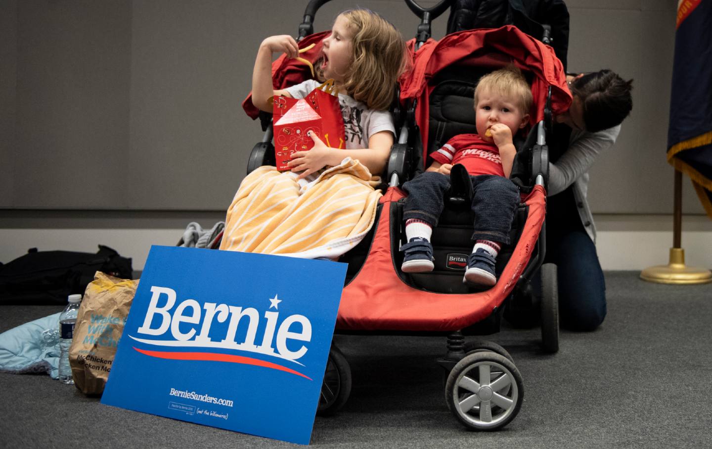 two children eat in their stroller at a satellite caucus