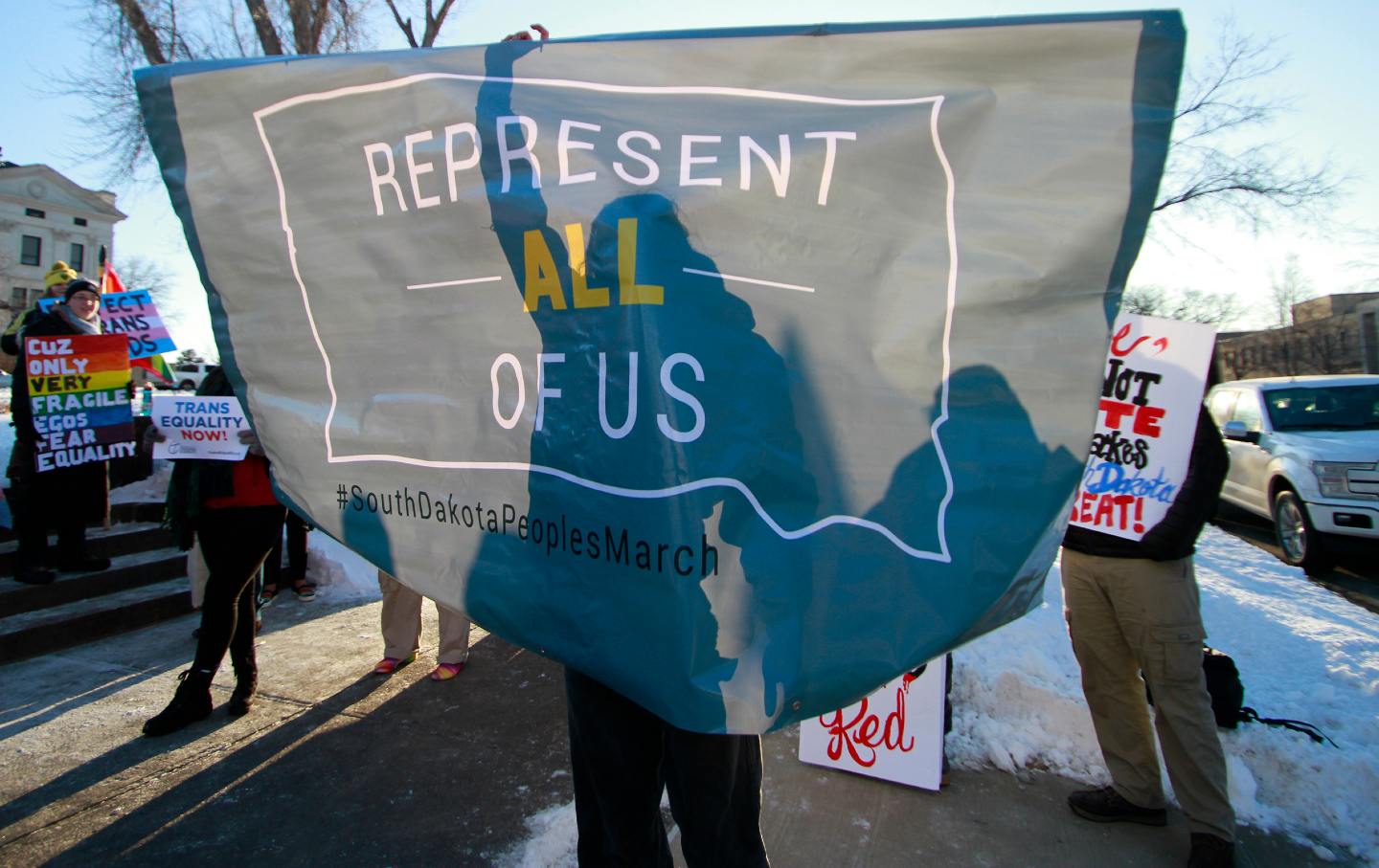 A protester unfurls a banner outside the South Dakota Capitol