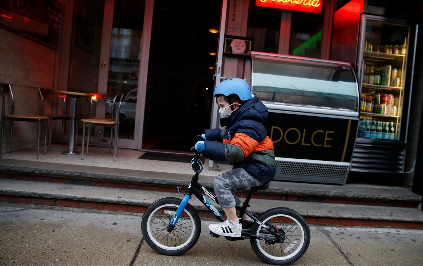 A boy rides his bike through Boston with a mask