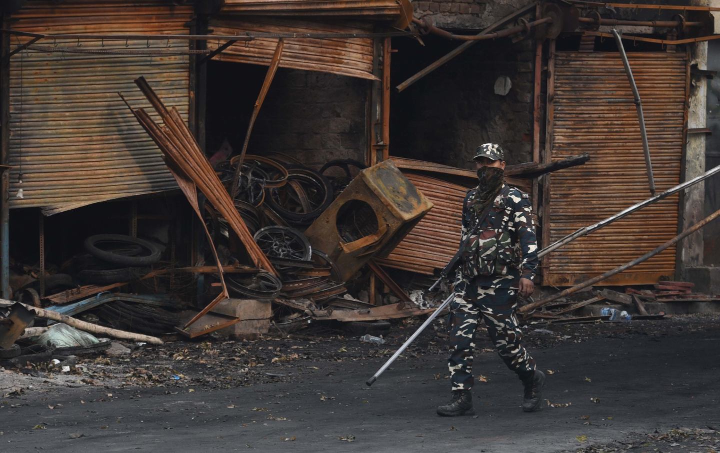 Sashastra Seema Bal personnel walk past burnt and damaged shops
