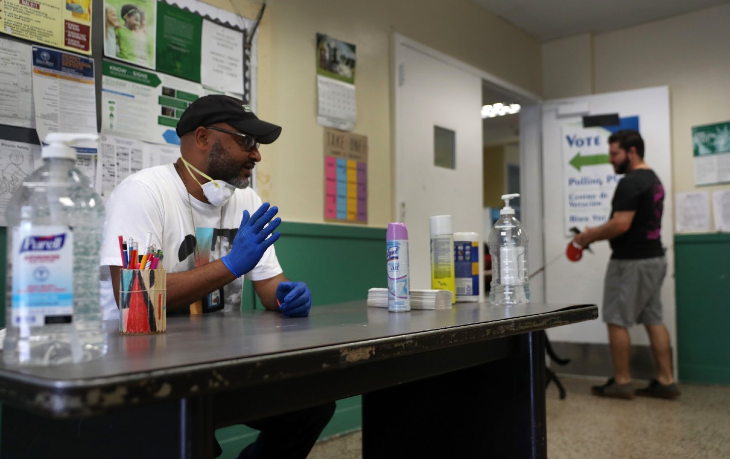 A voting precinct with a man wearing a cap seated at a table, waiting for voters.