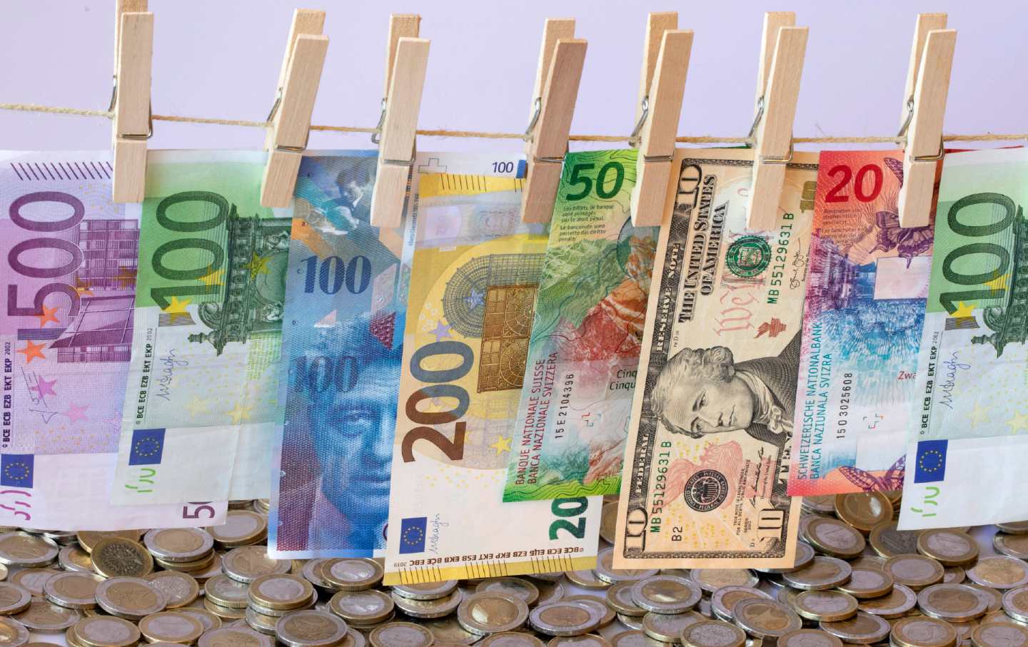 EURO, Swiss Franc and Dollar banknotes on a washing line and coins