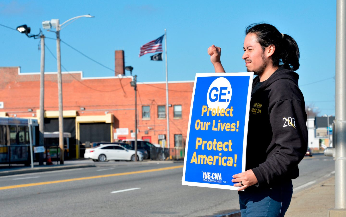 A GE worker stands outside the plant with a sign reading 