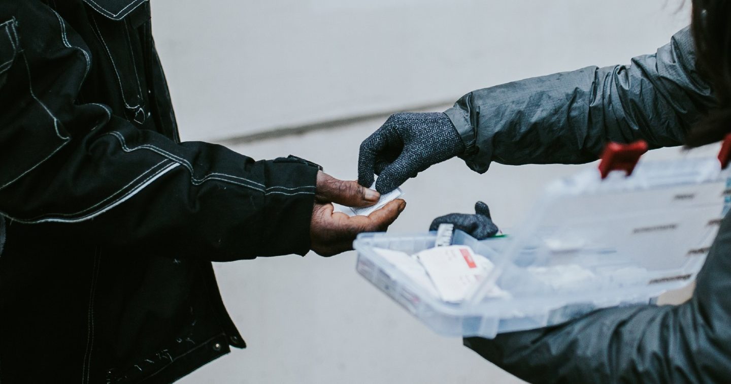 A member of Portland Street Medicine hands medical supplies to a homeless person.