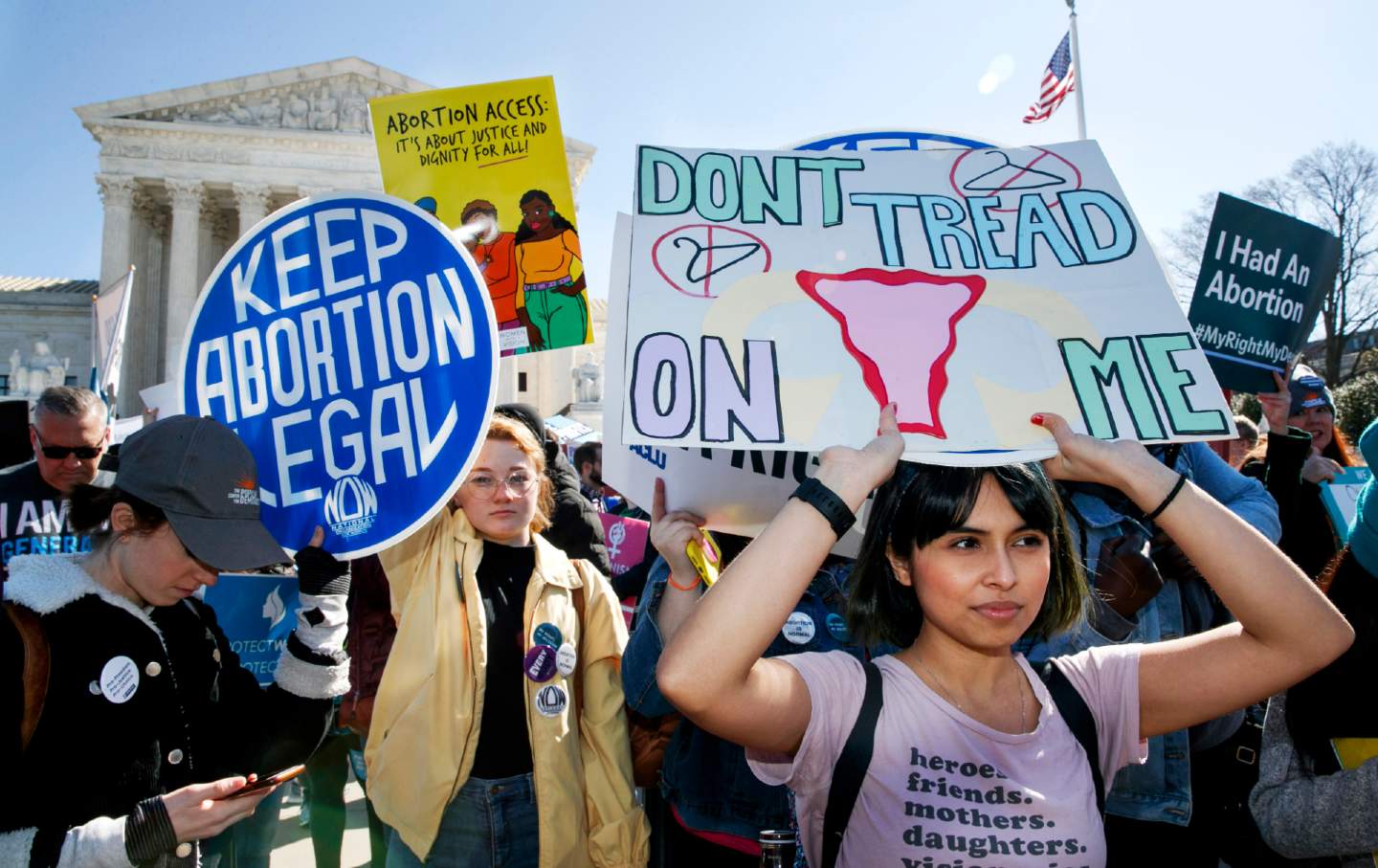 A group of people hold signs with slogans including 