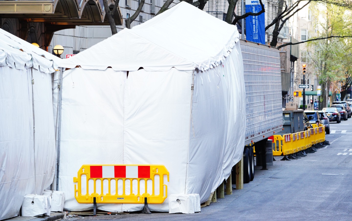 A trailer attached to a tent sits on the street near a hospital