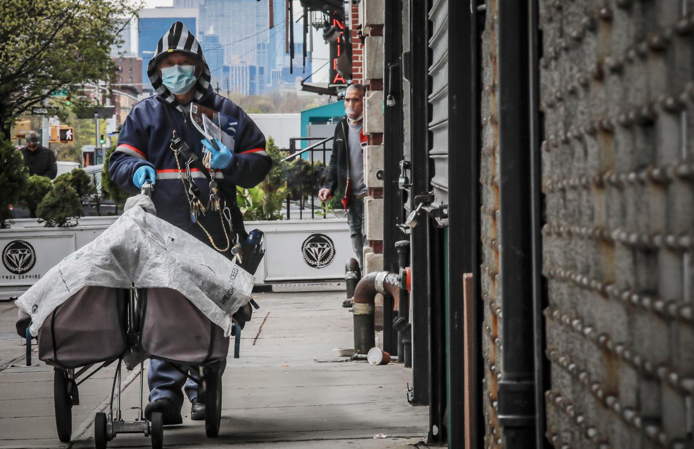 A postal worker delivers mail in Harlem with a mask