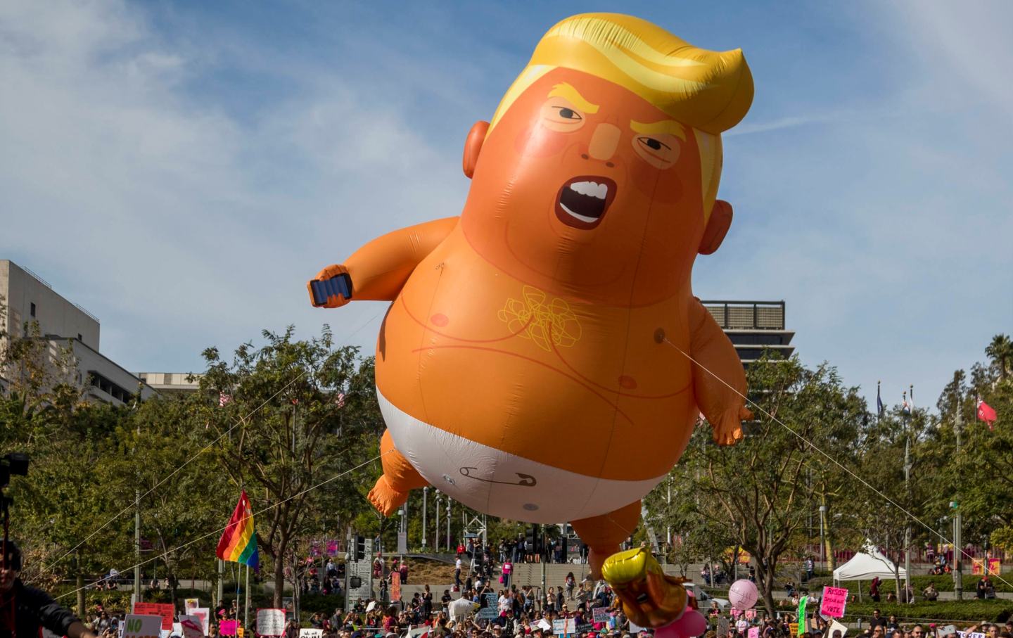 A balloon depicting Donald Trump in a diaper flies over those rallying at the 2020 Women's March in Los Angeles